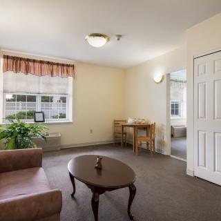 A cozy living room with a sofa, coffee table, and a large window providing natural light.