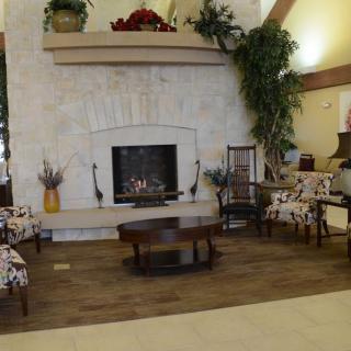 A cozy living room with a central fireplace, surrounded by stylish chairs and decor.
