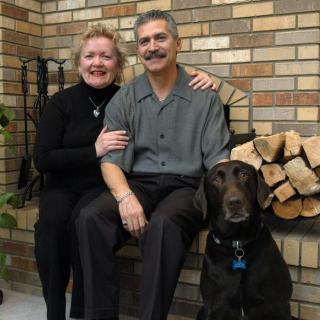 A couple sitting by a fireplace with their dog.