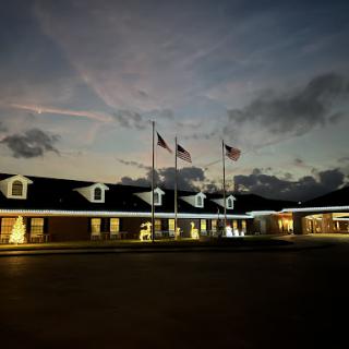 A building illuminated at night, featuring flags and a beautiful sky.