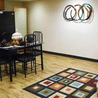 A modern dining area with artistic wall decor and a colorful geometric rug.