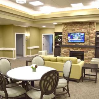 A cozy living area with comfortable seating, a mounted television above a stone fireplace, and a round table for gatherings.