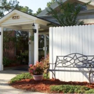 A welcoming entrance to a building with a landscaped garden and a decorative bench.