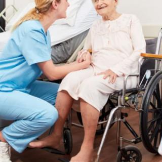 A nurse interacting with an elderly patient in a wheelchair.
