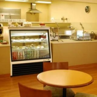 An empty cafe interior with a table, chairs, and a beverage fridge.