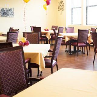 A well-lit dining area with arranged tables and chairs, decorated with balloons.