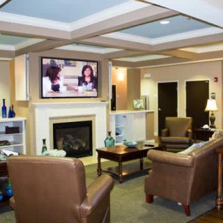 A cozy living room featuring a fireplace, comfortable seating, and a large television.