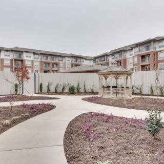 A modern apartment complex with a landscaped outdoor area featuring a pathway and a gazebo.