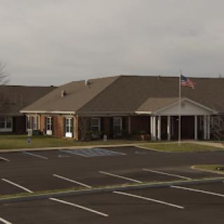 A residential building with a parking lot and an American flag, set against a cloudy sky.