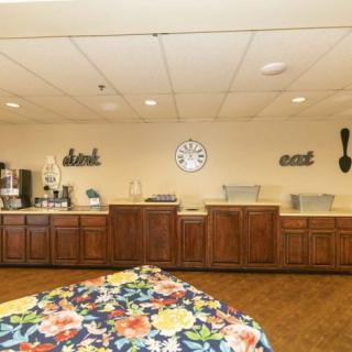 A self-service buffet area with a coffee station and decorative elements on the wall.