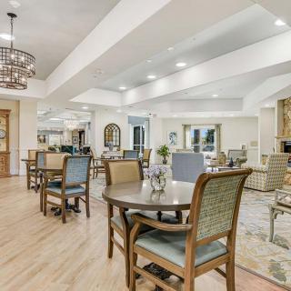 A well-lit and elegantly furnished dining area with several tables and chairs, featuring modern decor and design elements.