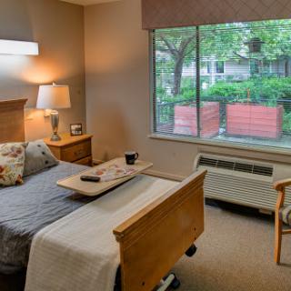 A cozy bedroom with a view of greenery outside the window.