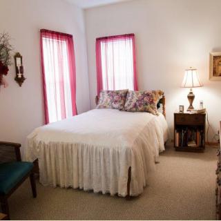 A cozy bedroom with a neatly made bed, side table with a lamp, and decorative curtains.
