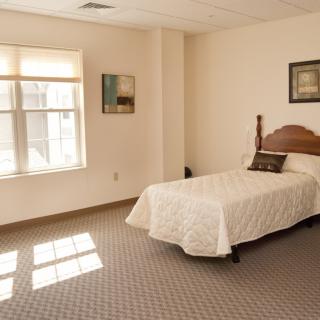 A minimalist bedroom with a single bed and decorative art on the walls.