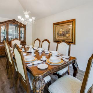 Elegant dining room setup with a richly decorated table, chandelier, and classic china cabinet.