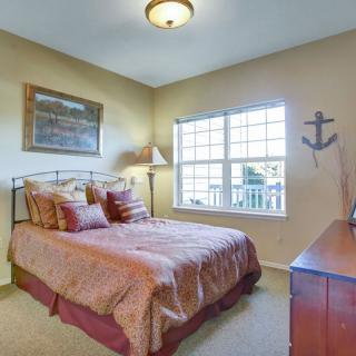 A cozy bedroom with a neatly made bed, warm lighting, and nautical decor on the wall.