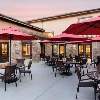 Outdoor patio area of a restaurant with red umbrellas at sunset.