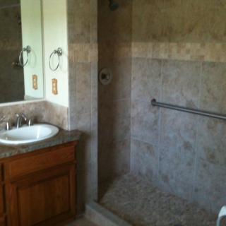 A bathroom featuring a sink with a mirror and a tiled shower area.