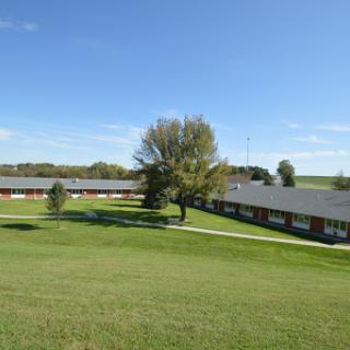 A serene view of a community building surrounded by lush greenery and a clear blue sky.