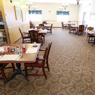 An empty dining area with several tables and chairs arranged on a carpeted floor.