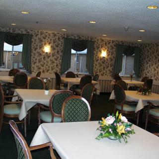 A spacious and elegantly arranged dining room featuring tables set for guests, adorned with floral centerpieces.