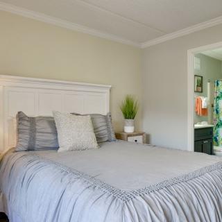 A cozy bedroom with a neatly made bed, complemented by pillows and a nightstand adorned with a small potted plant.
