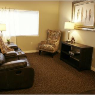 A cozy living room with a comfortable chair, lamps, and a decorative painting.