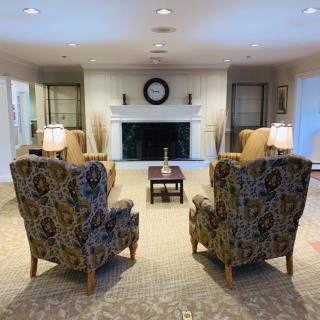 A cozy living room with patterned armchairs facing a fireplace, accented by warm lighting and decorative elements.