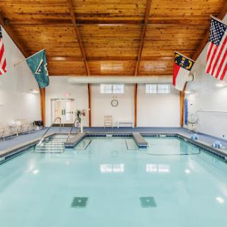 A serene indoor swimming pool featuring a wooden ceiling and various flags adorning the walls.