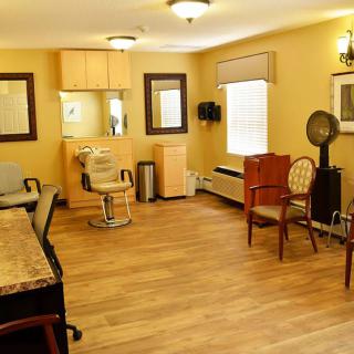 A cozy hair salon with wooden flooring, mirrors, and comfortable seating.
