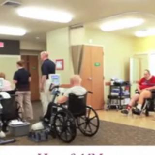 A rehabilitation clinic with patients in wheelchairs and healthcare professionals providing assistance.
