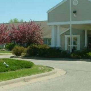 A building with a driveway and landscaped grounds featuring trees in bloom.