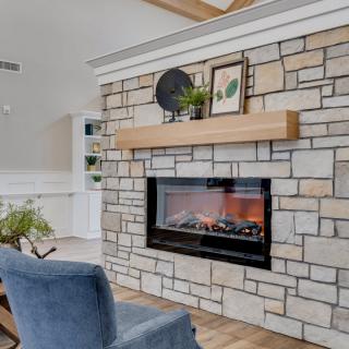 A modern living room with a stone fireplace and cozy armchair.