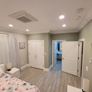 A modern, minimalist bedroom with light-colored flooring and recessed lighting.