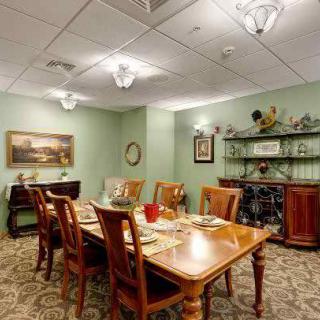 A well-decorated dining room with a wooden table and chairs, set for a meal. The room features artwork on the walls, a sideboard, and elegant lighting fixtures.
