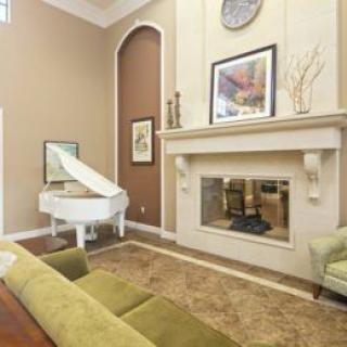 A cozy living room featuring a white grand piano, an elegant fireplace, and stylish decor.