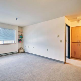 An empty room with carpet flooring and a large window, featuring a doorway leading to another area.