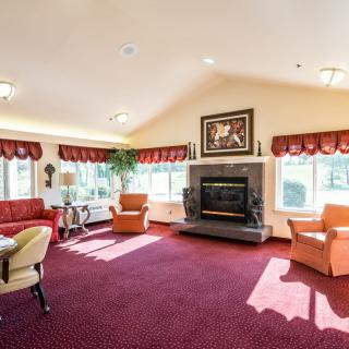 A spacious living room with a fireplace, red carpet, and multiple seating areas.