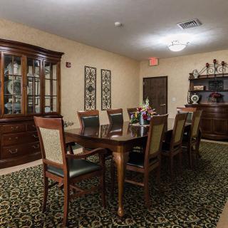 A well-furnished dining room with a large table and chairs, carpeted floor, and a china cabinet.