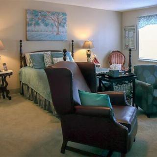 A cozy and well-decorated bedroom featuring a large bed, armchairs, and warm lighting.