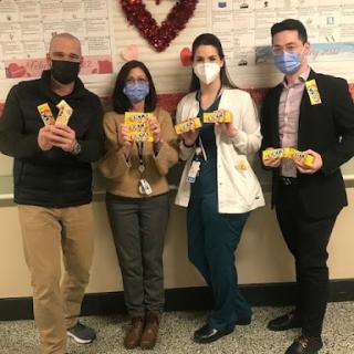 A group of healthcare professionals celebrating an event with smiles and creativity while wearing masks.