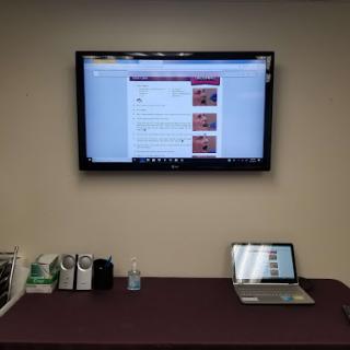 A modern office setup featuring a laptop and a TV display.