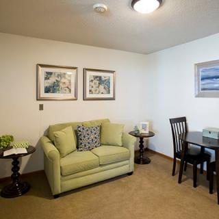 A cozy living room with a green sofa and wall art.