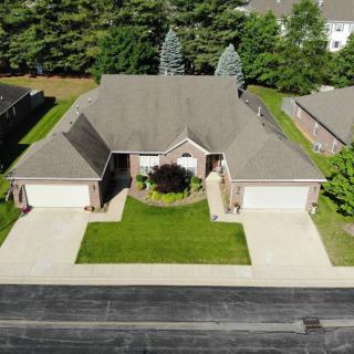 Aerial view of a duplex house with driveways and a well-maintained lawn.