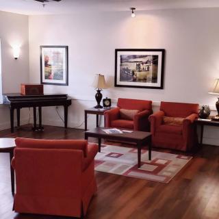 A cozy living room with red armchairs, a coffee table, and artwork adorning the walls.