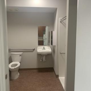 A clean and simple bathroom with a toilet, sink, and shower.