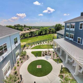 A modern courtyard surrounded by buildings with a landscaped lawn and clear blue sky.