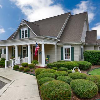 A charming suburban house with a manicured garden and a welcoming porch.
