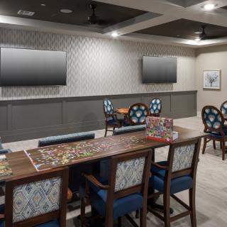 A modern game room with a puzzle on the table and wall-mounted televisions.