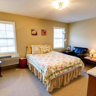 A cozy bedroom with a floral bedspread, two windows, and warm lighting.